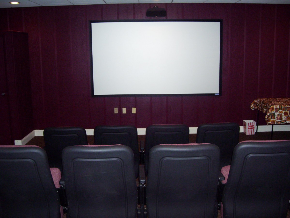 A cozy home theater with comfortable seating facing a large movie screen.