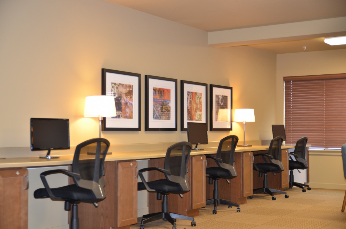 A modern office workspace featuring desks with computers, chairs, and decorative artwork.