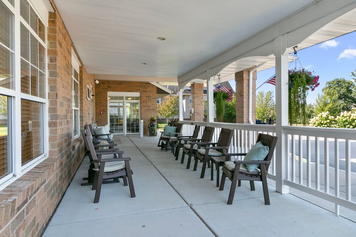 A spacious porch with multiple chairs arranged for outdoor seating.