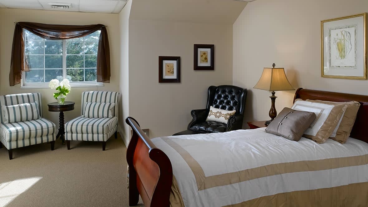 A cozy bedroom with a wooden bed, armchair, and window.