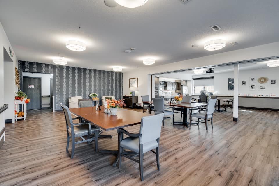 A modern dining area with wooden flooring and neatly arranged tables and chairs.