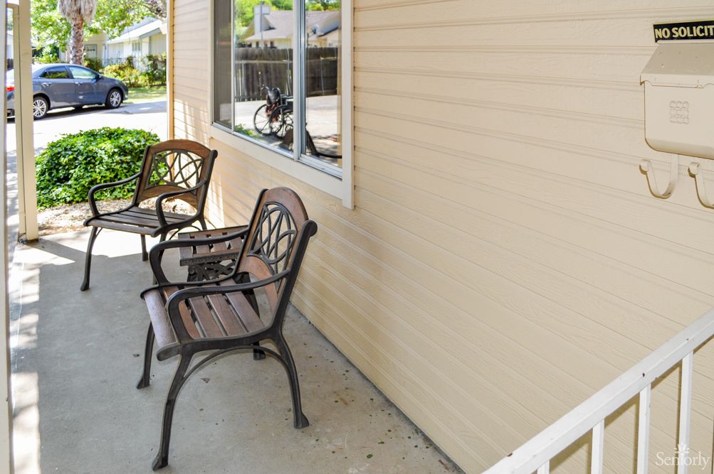 A small porch with two chairs next to a window.