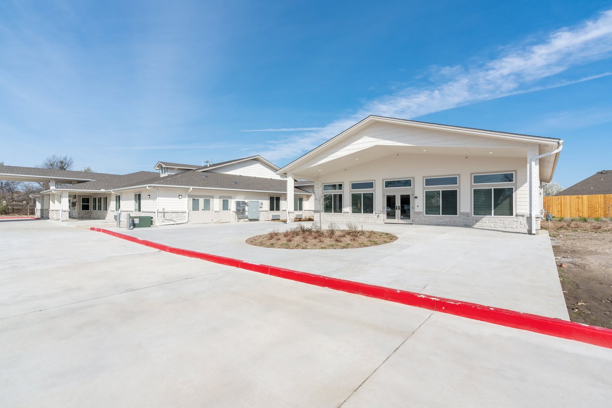 A modern commercial building with a spacious concrete driveway and clear blue sky.