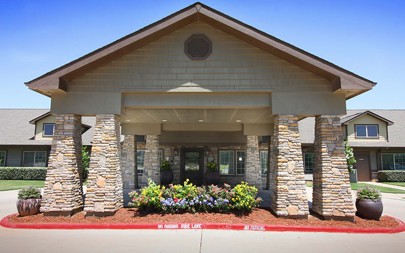 A building entrance featuring stone columns and landscaped greenery.