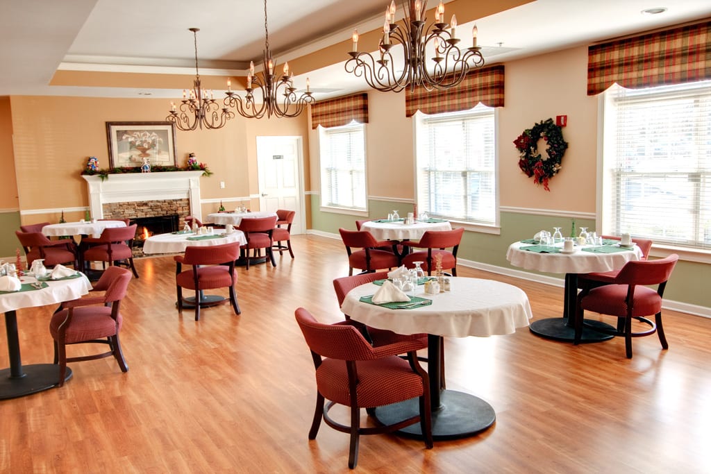A neatly arranged dining room with elegant chandeliers and wooden flooring.
