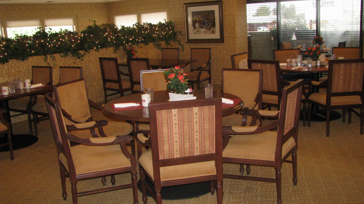 A cozy indoor dining area with a round table and several chairs, decorated with plants.