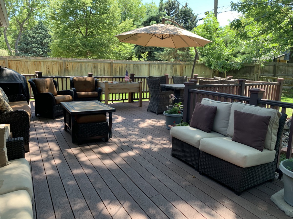 A sunny outdoor deck with comfortable patio furniture and an umbrella.