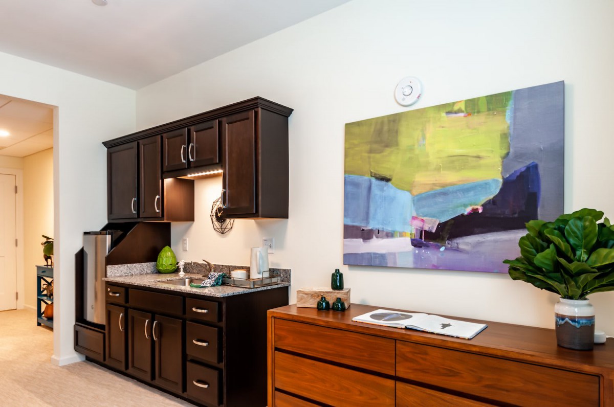 A modern kitchen featuring dark cabinets and colorful artwork on the wall.
