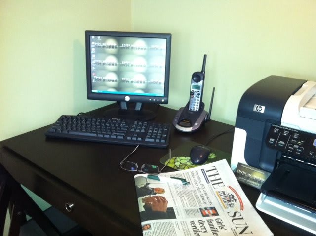 A tidy office desk with a computer, telephone, and newspaper.