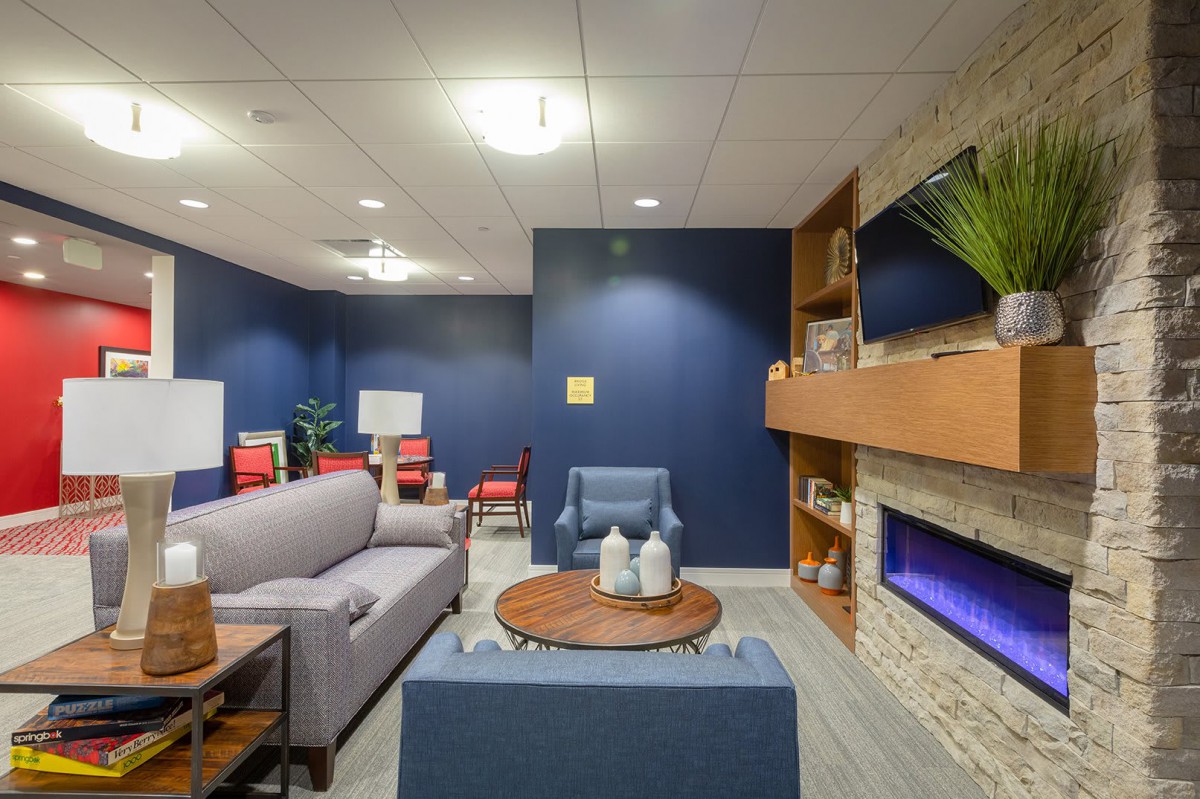 A modern living room featuring a cozy seating area with blue walls and a fireplace.