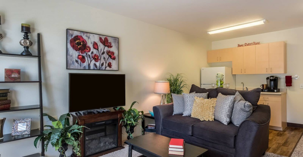 A cozy living room with a couch, television, and decorative artwork.