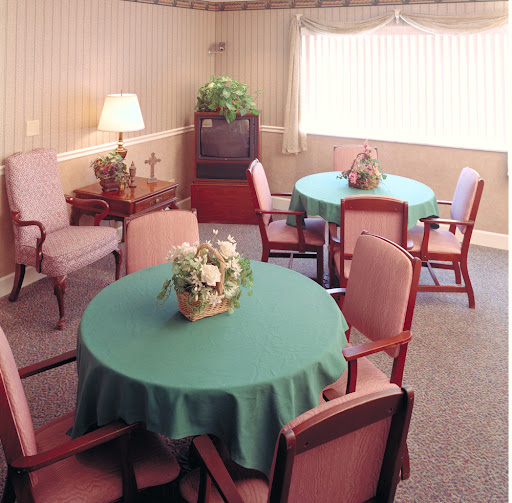 A cozy seating area featuring round tables with green tablecloths and comfortable chairs.