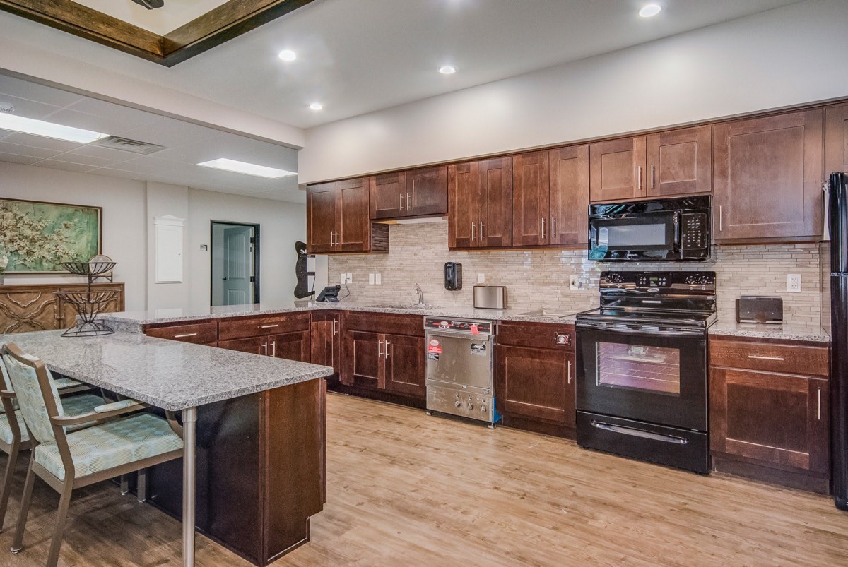 A modern kitchen with wooden cabinets and a central island, featuring stainless steel appliances and an open layout.
