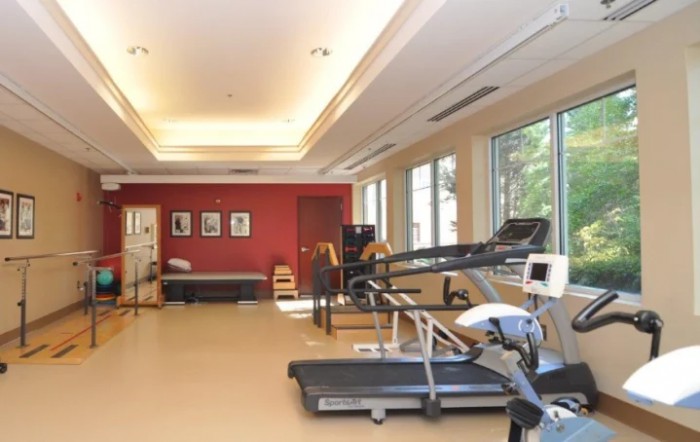 A modern gym with exercise equipment and large windows.