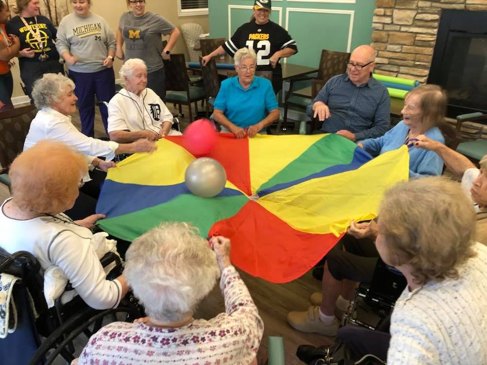 A group of elderly individuals participating in a parachute game, enjoying a lively community activity together.