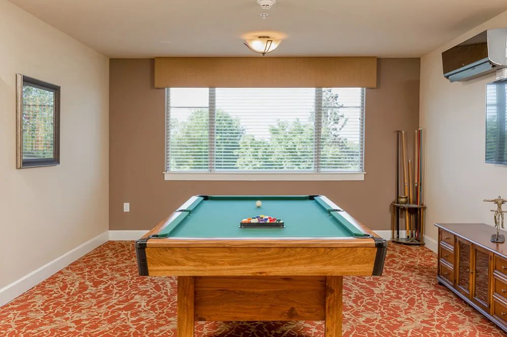 A spacious game room featuring a pool table and cue sticks.