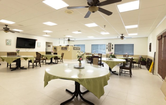 A spacious and well-lit dining room with round tables and ceiling fans.