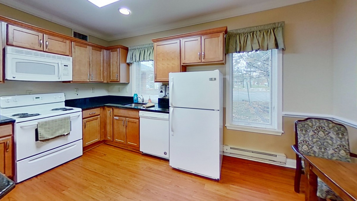 A spacious kitchen featuring wooden cabinets, a white refrigerator, and a large window.