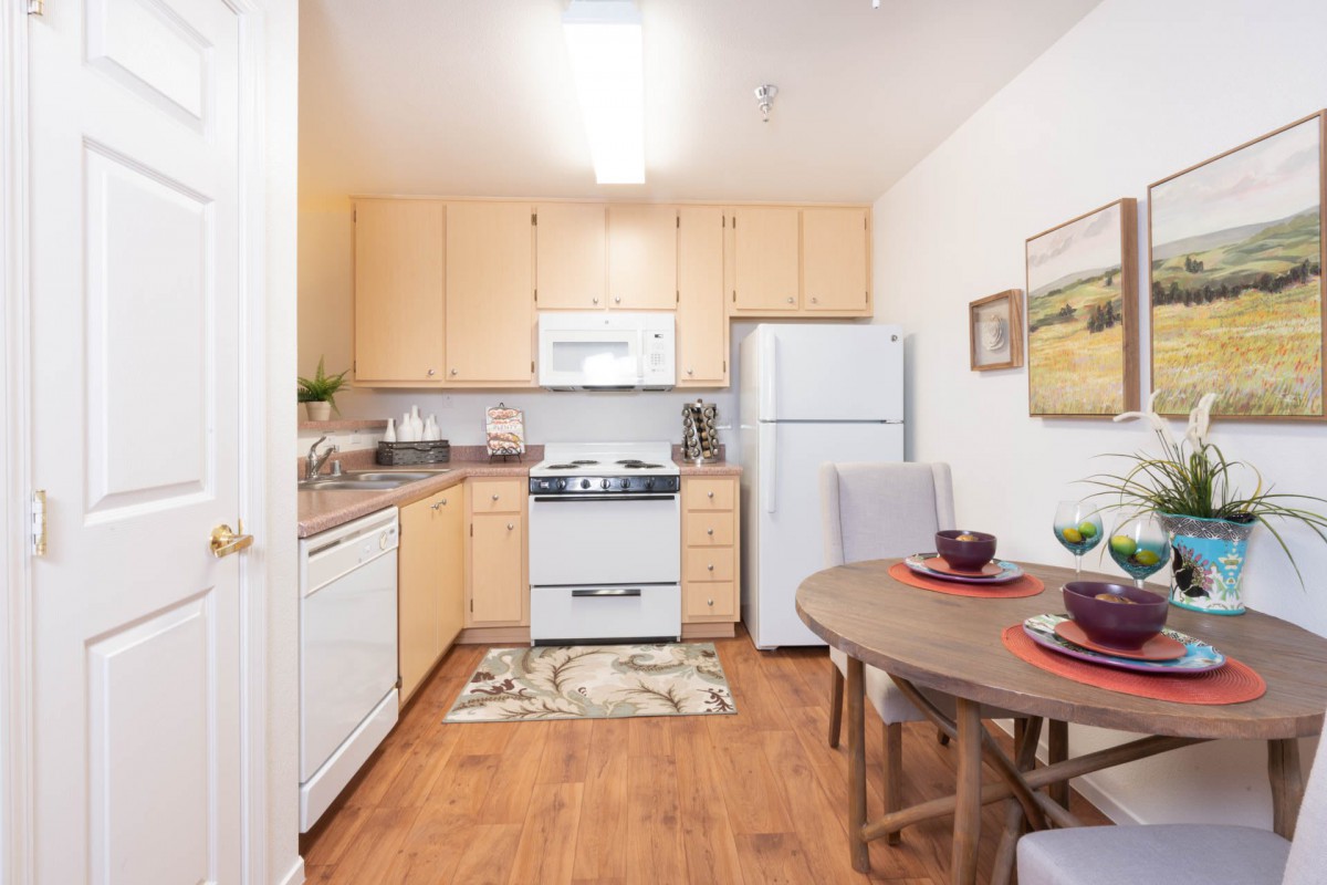 Cozy apartment kitchen with wooden cabinets and a small dining area.