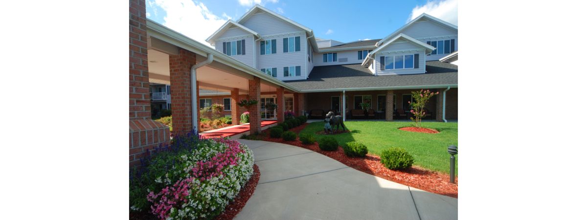 A well-maintained building with a landscaped entrance and flower beds on a sunny day.