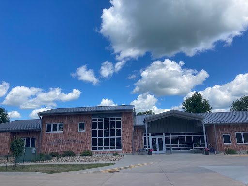 A modern brick building under a clear blue sky adorned with fluffy clouds.