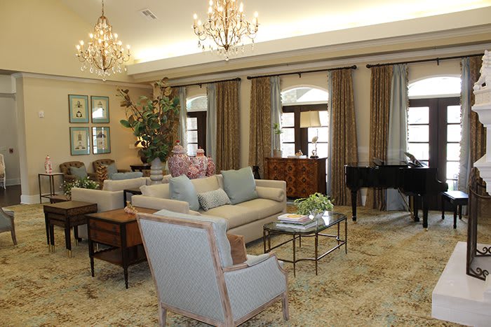 A luxurious living room with elegant chandeliers, comfortable sofas, and a piano.