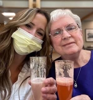 Two people enjoying a drink together; one is wearing a mask.