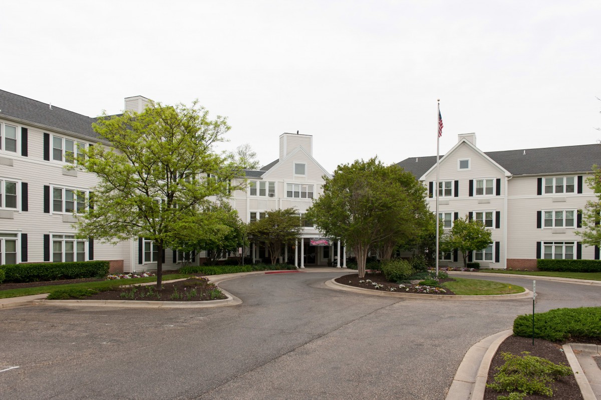 A residential building with a driveway and surrounding trees.