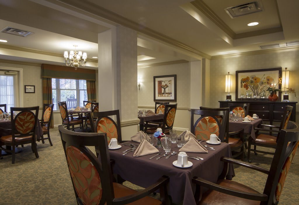 A cozy and elegantly set dining room with tables prepared for guests.