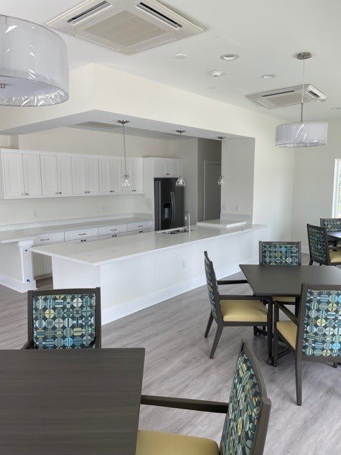 A modern kitchen with white cabinets and an adjoining dining area featuring stylish tables and chairs.