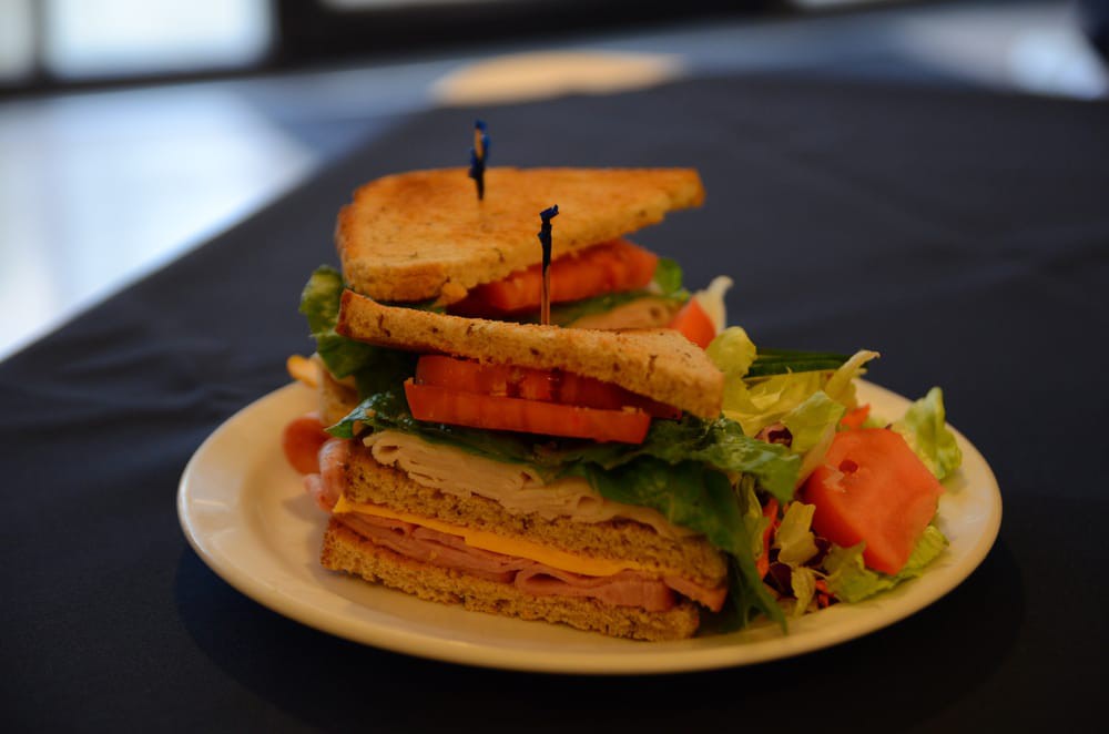 A stacked club sandwich with layers of turkey, cheese, lettuce, and tomato on toasted bread.