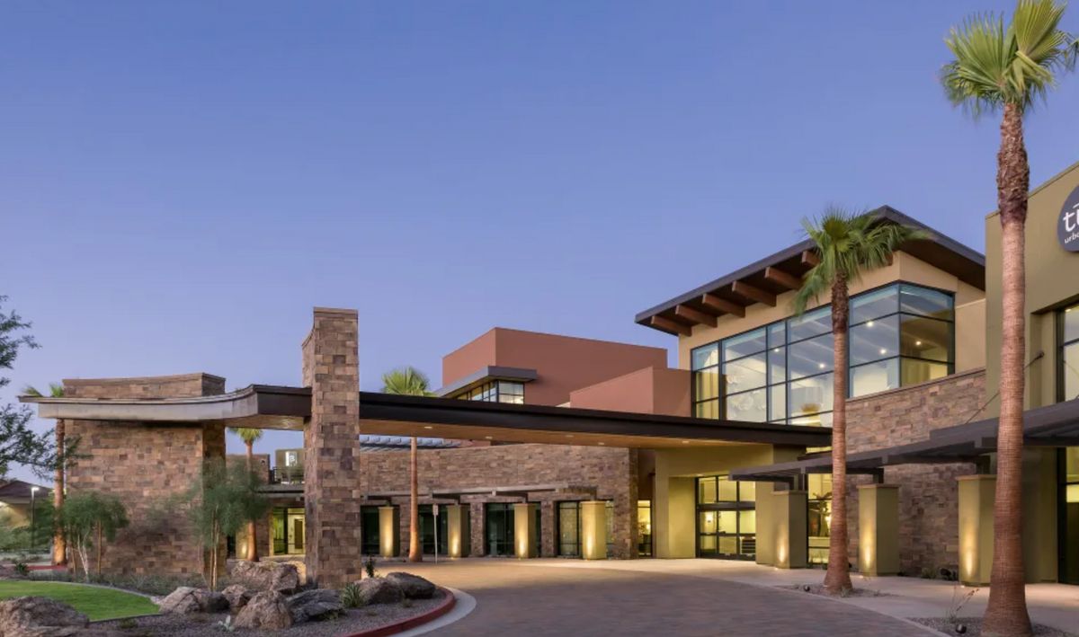 A modern building with large glass windows and a stone exterior at dusk.