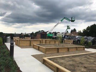 Construction site with wooden raised garden beds under an overcast sky.