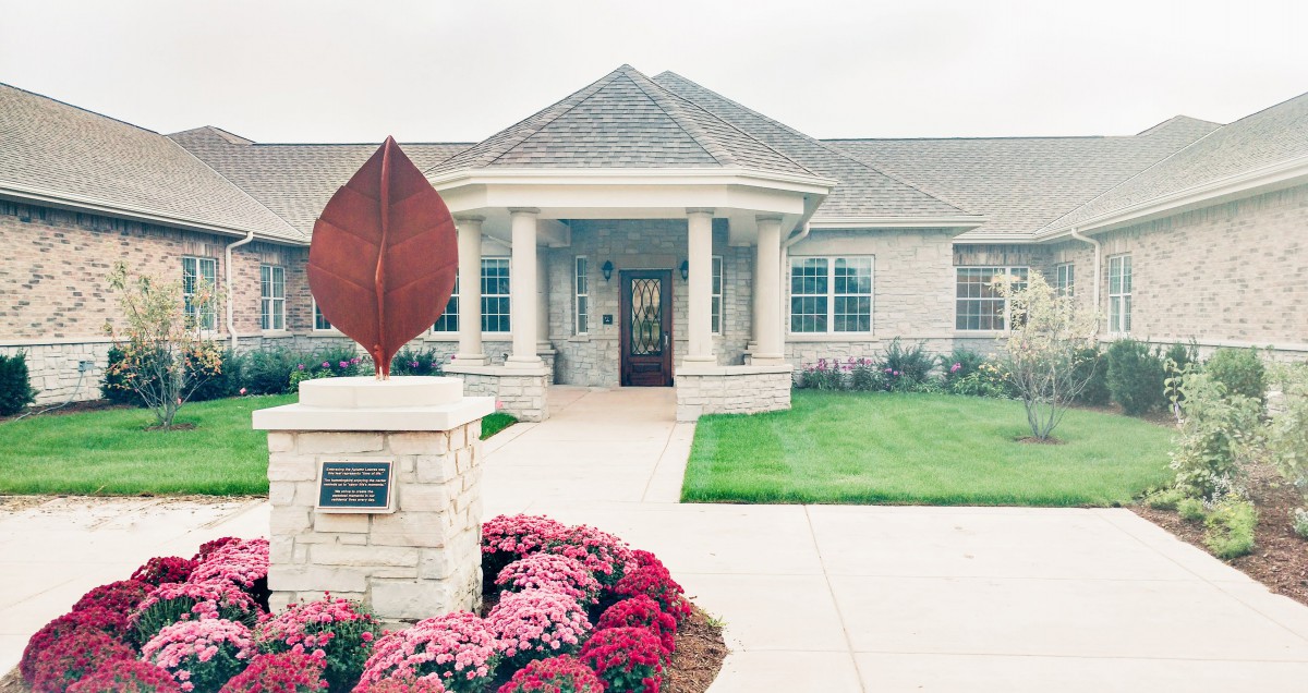 A well-maintained building entrance with a sculpture and landscaped garden.