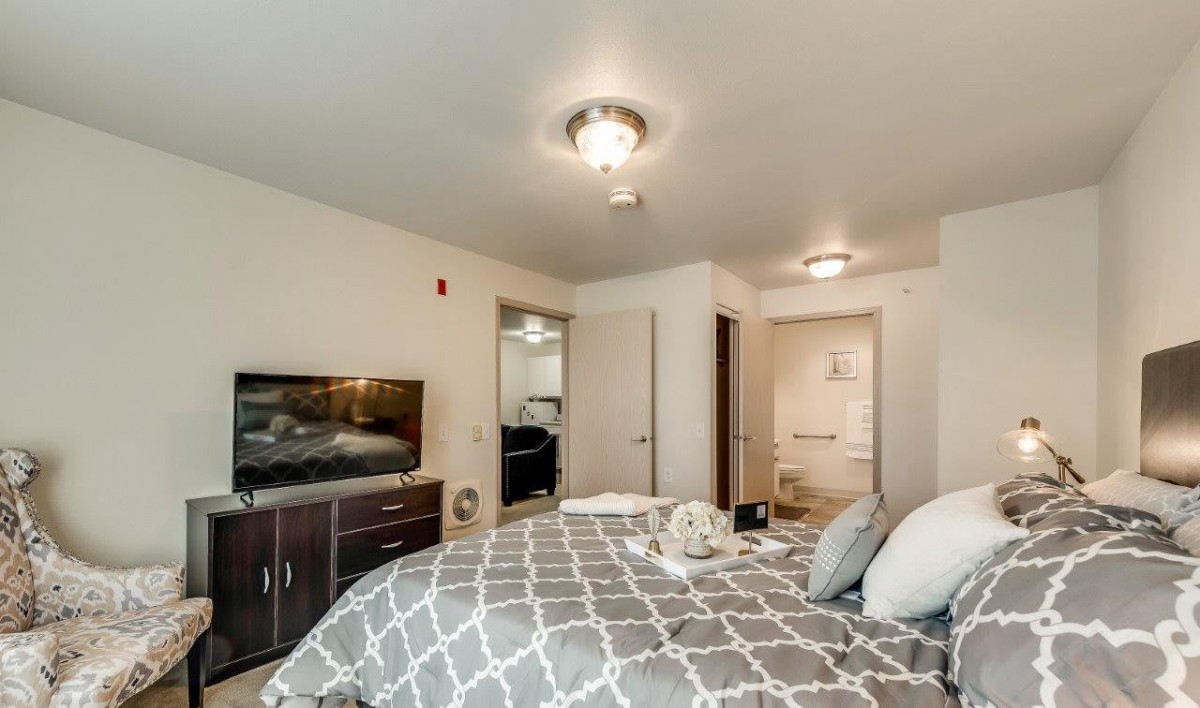A modern bedroom interior featuring a comfortable bed, a TV, and stylish decor.