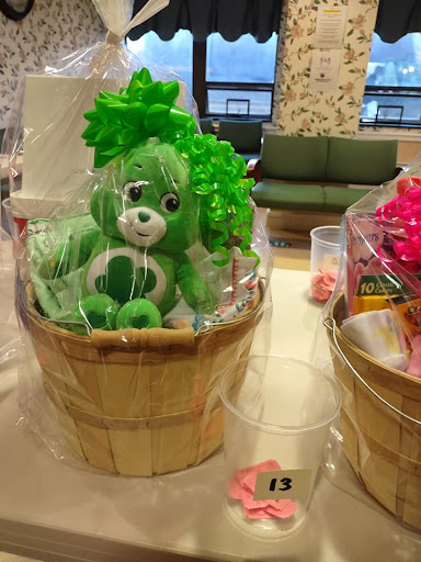 A cheerful green stuffed animal nestled in a decorative basket, perfect for gifting.