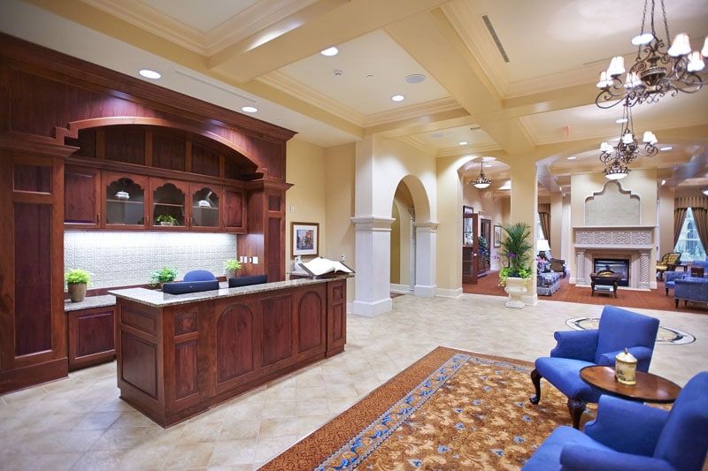 A spacious and elegantly designed office reception area with a wooden desk, comfortable seating, and decorative elements.