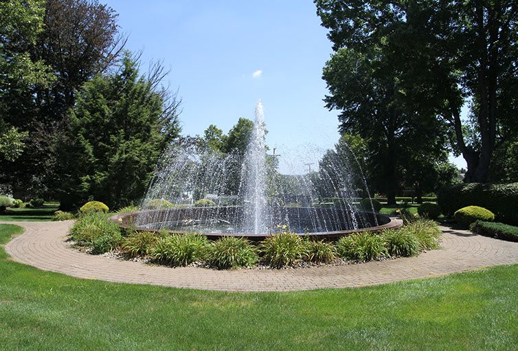 A scenic fountain surrounded by greenery in a tranquil garden setting.