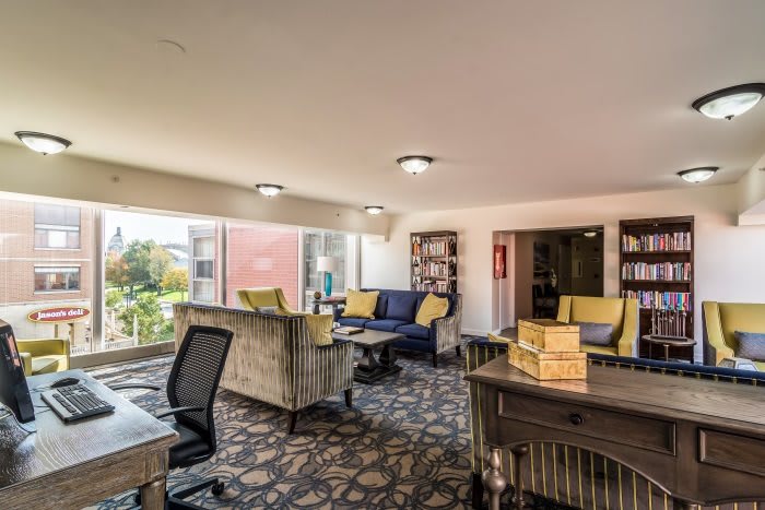 A modern office space with comfortable seating, workstations, and large windows providing natural light.