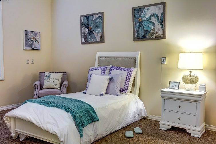 A cozy bedroom with a single bed, nightstand, and decorative artwork on the walls.
