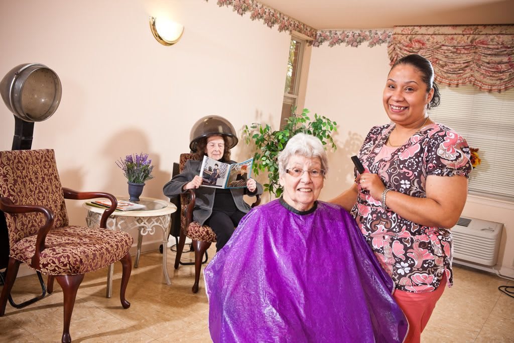 An elderly woman gets her hair done at the salon, enjoying the company of her hairdresser.