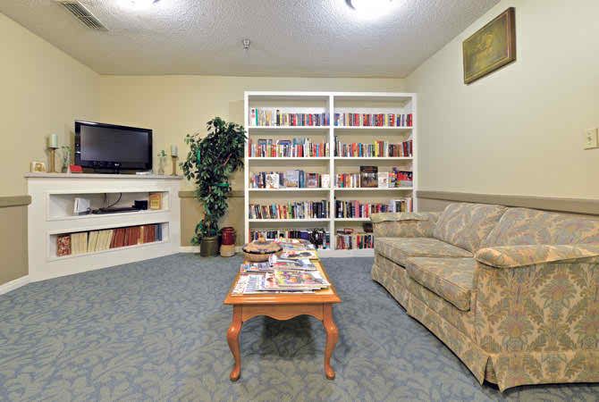A cozy living room with a bookshelf filled with books, a sofa, a coffee table, and a television.