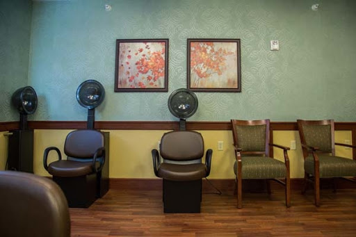A cozy waiting area in a salon featuring comfortable chairs and decorative artwork.
