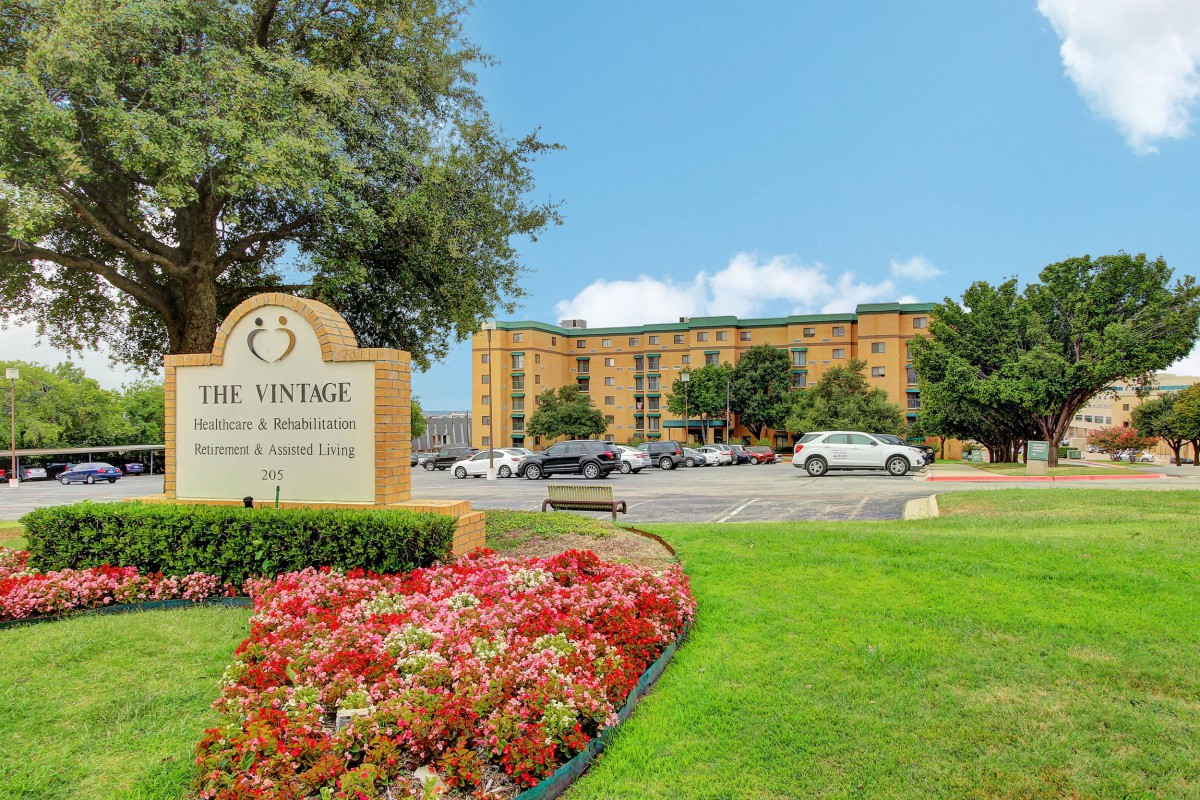 A residential apartment complex with well-maintained landscaping and parking area.