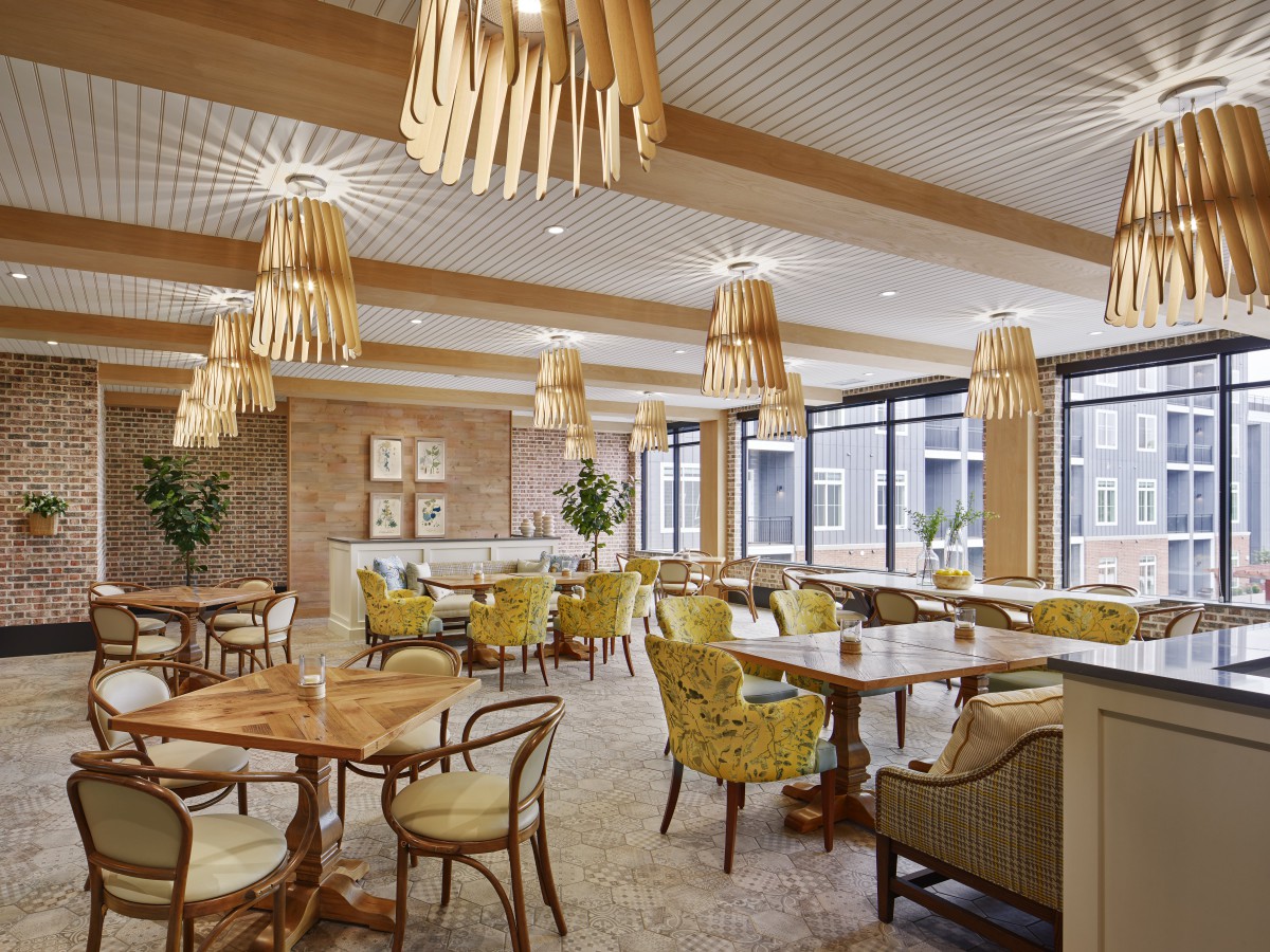 A modern restaurant interior featuring wooden decor, comfortable seating, and stylish chandeliers.