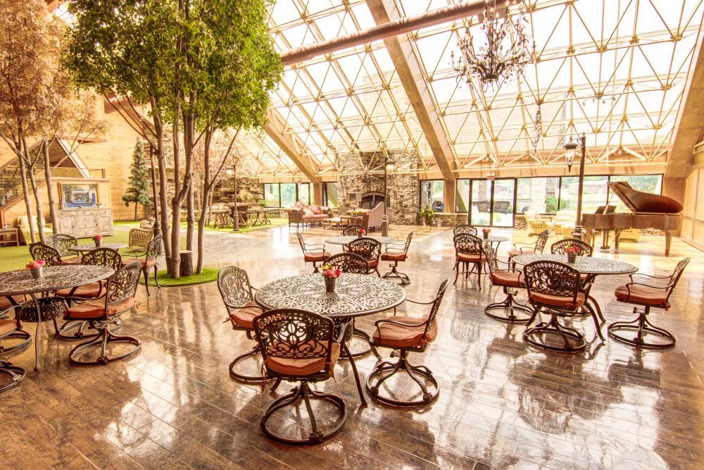 A spacious dining area with a glass ceiling, filled with natural light and elegant furnishings.
