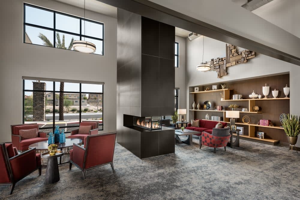 A modern living room with a central fireplace and large windows.