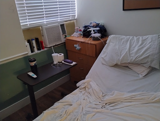 A cozy bedroom with an unmade bed and a nightstand filled with personal items.