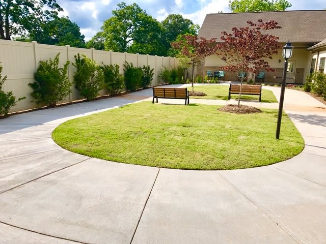 A well-maintained garden with a circular pathway, benches, and lush trees.