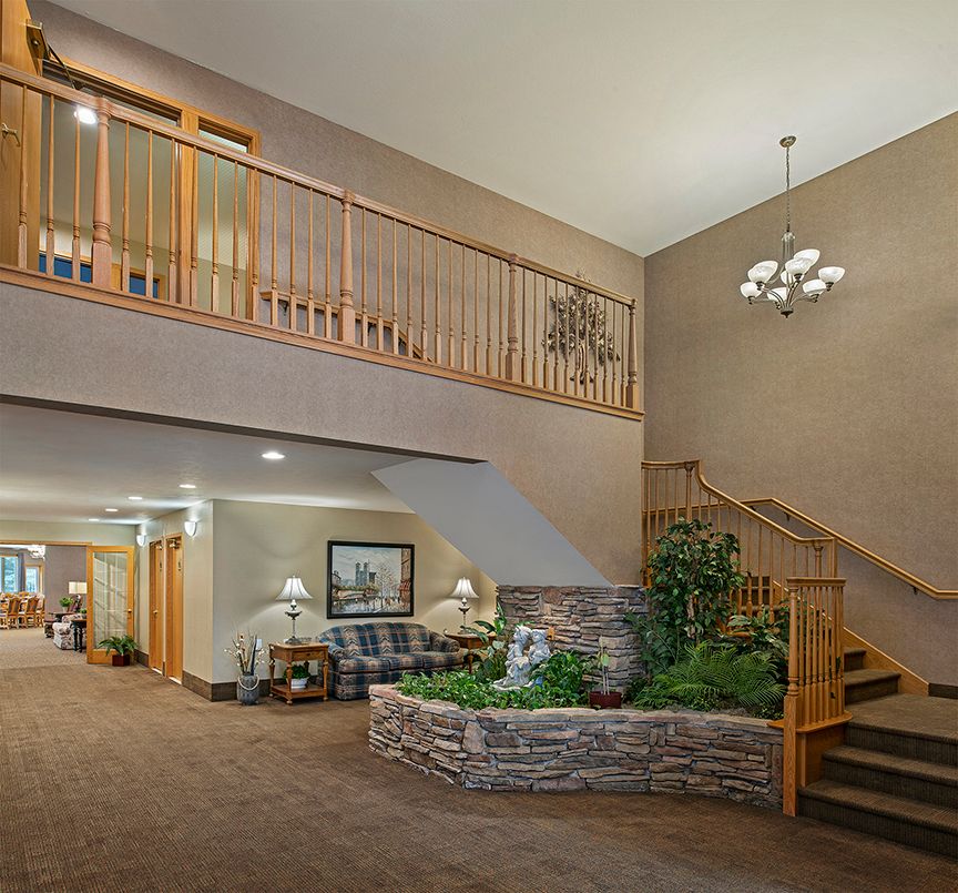 Spacious lobby interior with a staircase, seating area, and decorative plants.